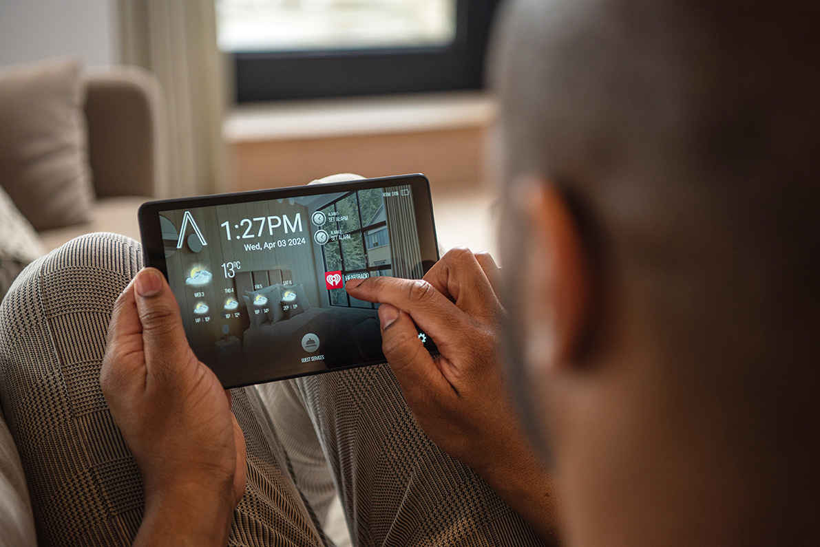 Guest using a smart tablet in a serviced apartment to access room controls and services