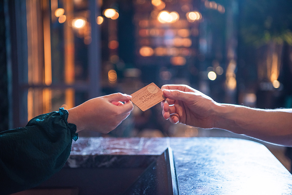 Close-up of a guest receiving a branded key card at a serviced apartment reception desk