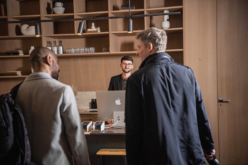 Two men checking in to a hotel, with a man behind a desk and computer