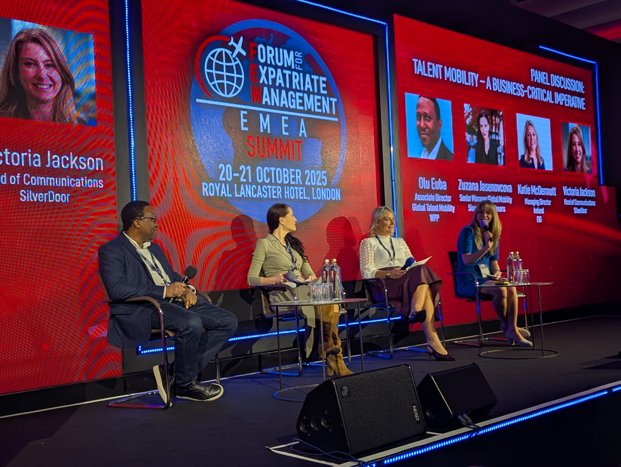 Panel discussion at the Forum for Expatriate Management EMEA Summit 2025 held at the Royal Lancaster Hotel in London, featuring multiple speakers on stage with a large red digital backdrop displaying their names and event details.