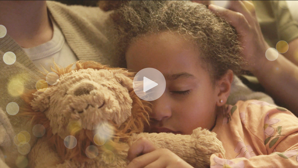 Sleeping girl who stars in SilverDoor Christmas Video with play button to watch the video.