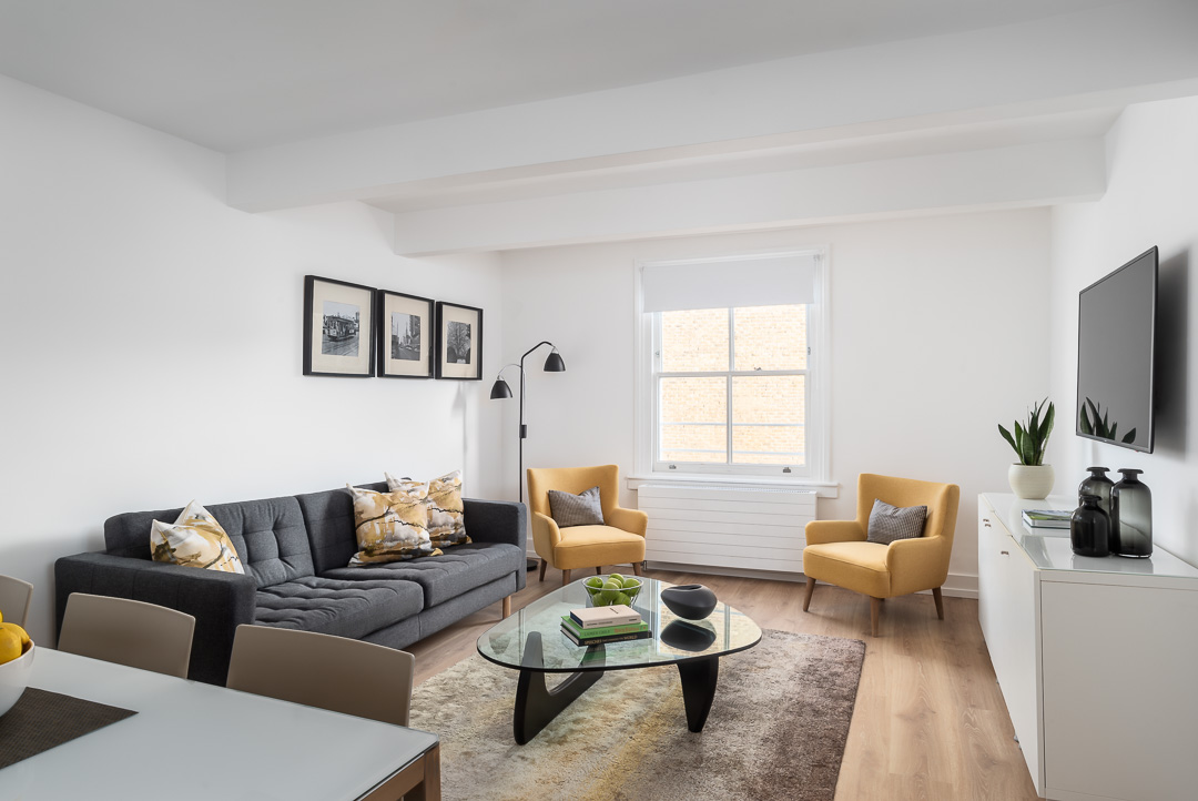 A living room, with bright natural lighting, white painted walls, a TV and modern interior