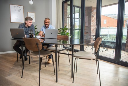 Two men sat at a table with computers