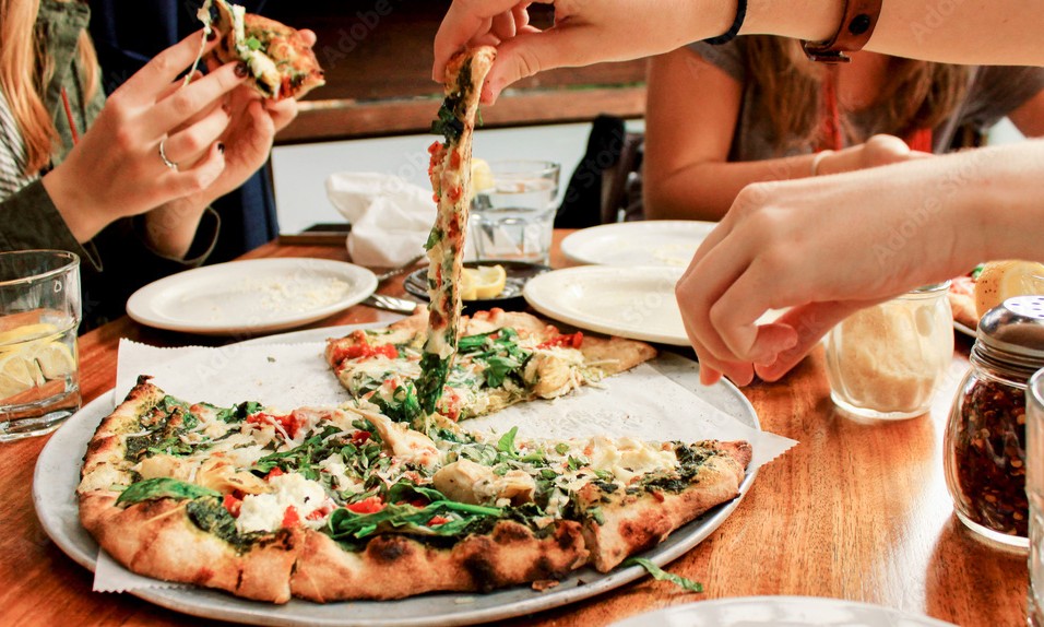 Group of people sharing a Greek-style pizza in New York City