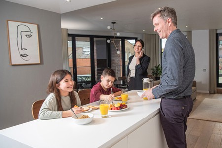 Family eating breakfast round a kitchen island