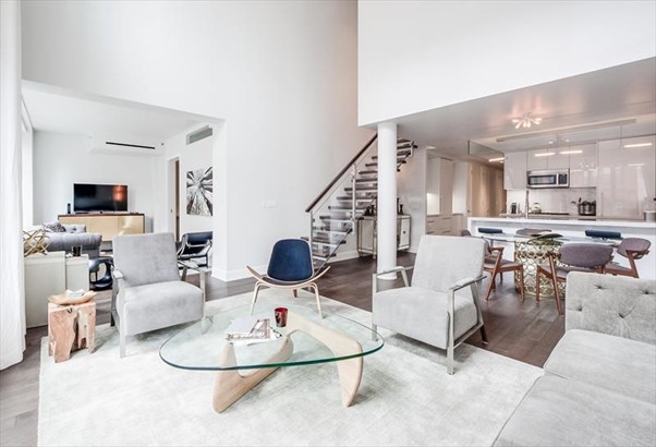 Open-plan living space with double-height ceilings, mid-century style chairs and fully equipped kitchen.