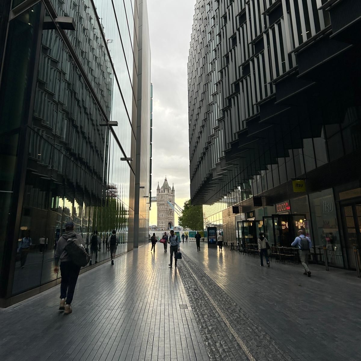 Modern office buildings leads and restaurants toward Tower Bridge on a cloudy morning