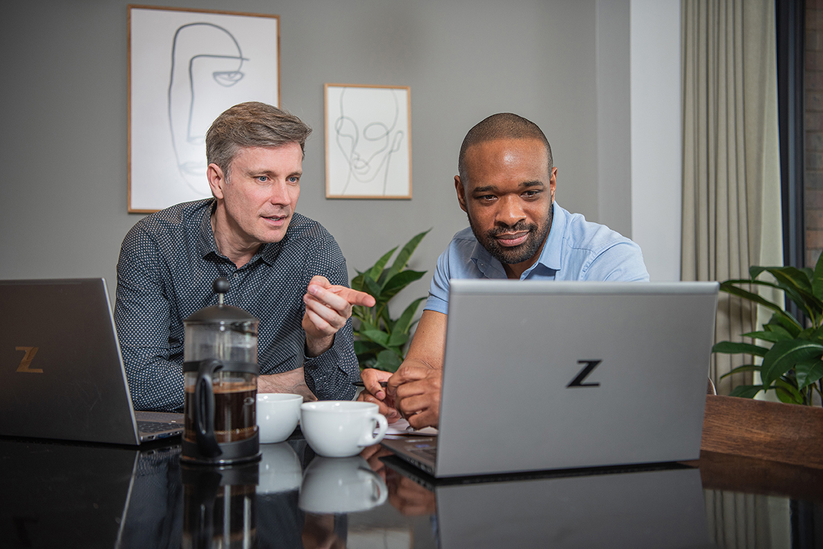 Two men in a serviced apartment having a serious discussion infront of work laptops