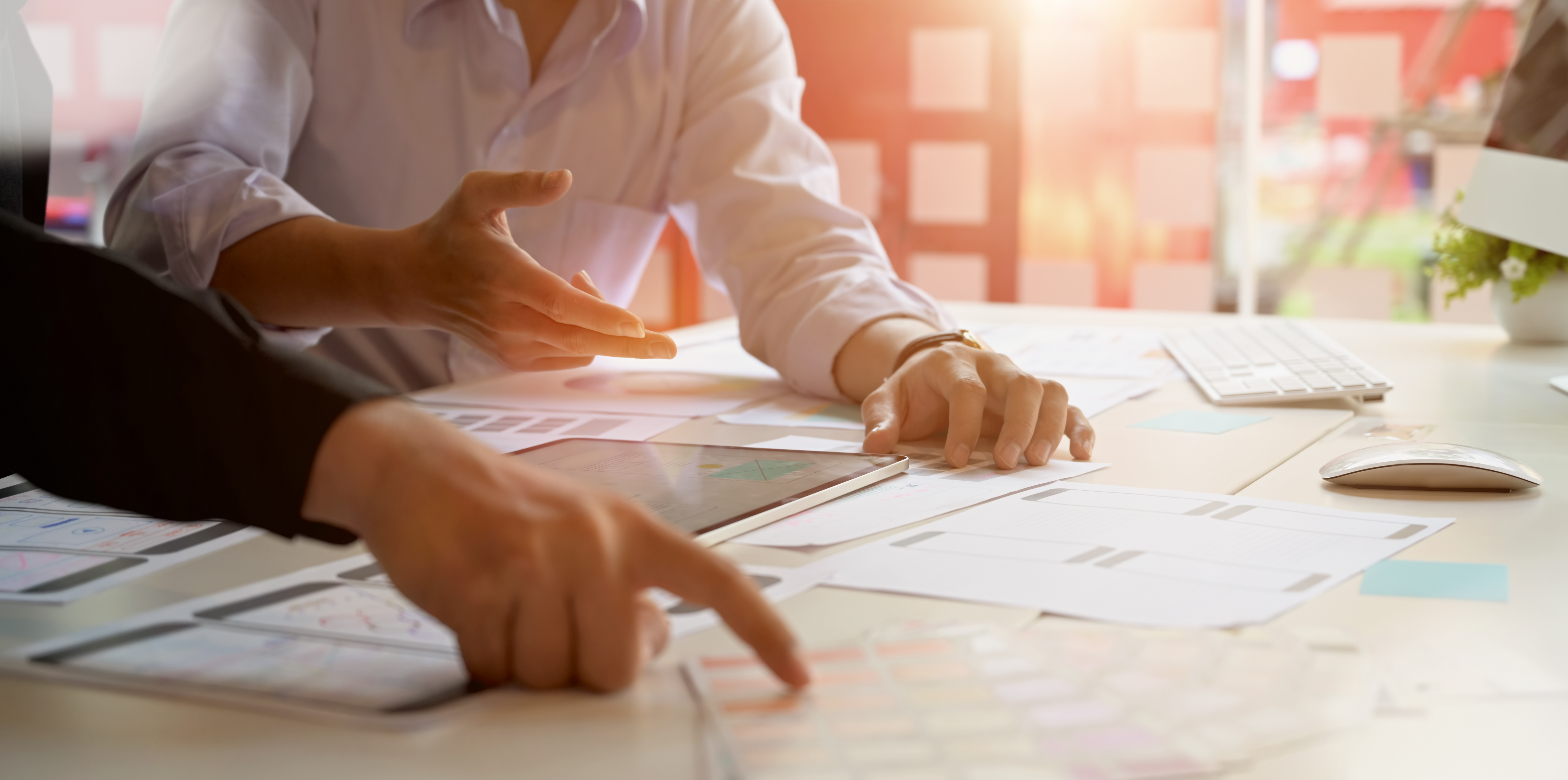 two people having a planning meeting at a table covered in papers and graphs