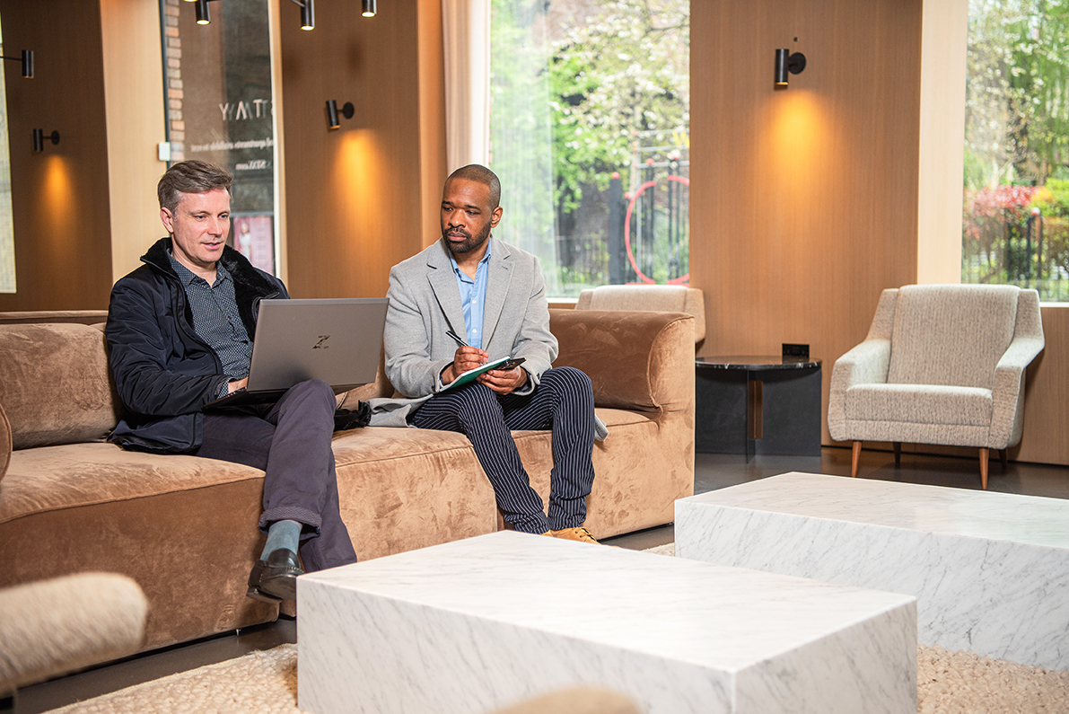 Two busiessmen having a serious discussion on the sofa in a serviced apartment